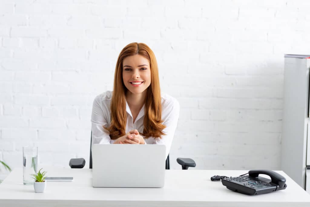Successful business women smiling while sitting at her desk with laptop.